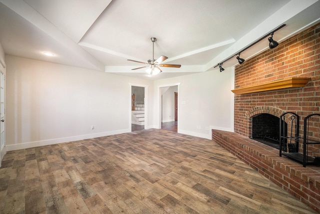 unfurnished living room featuring ceiling fan, a fireplace, wood finished floors, baseboards, and stairs
