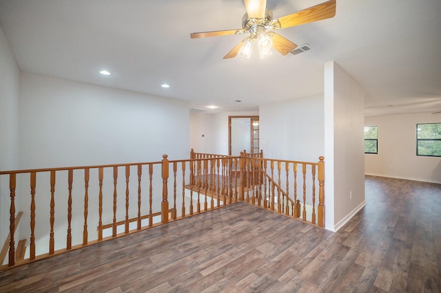 hallway featuring visible vents, wood finished floors, baseboards, recessed lighting, and an upstairs landing
