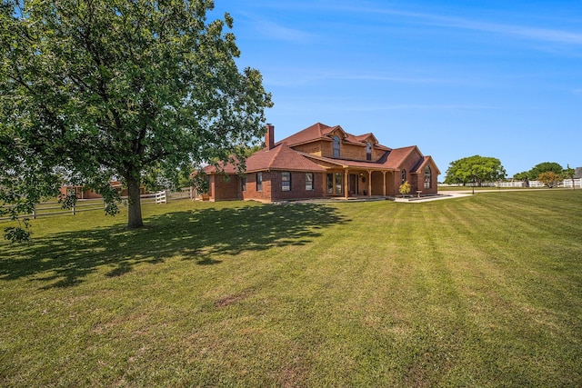 back of house featuring fence, covered porch, a chimney, brick siding, and a yard