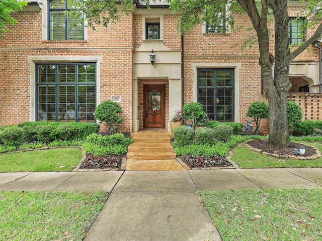 view of exterior entry featuring brick siding