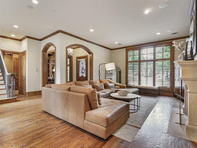 living room featuring arched walkways, ornamental molding, and wood finished floors