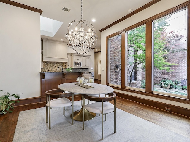 dining space featuring an inviting chandelier, crown molding, wood finished floors, and visible vents
