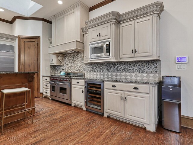 kitchen featuring built in refrigerator, a breakfast bar area, wood finished floors, and visible vents