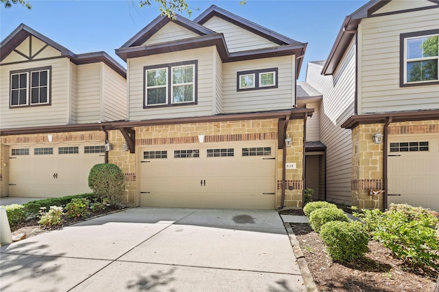 multi unit property featuring a garage, concrete driveway, and stone siding