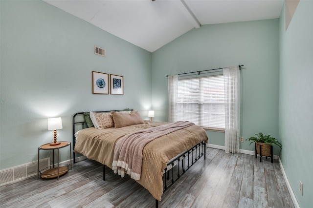 bedroom featuring baseboards, beamed ceiling, wood finished floors, and visible vents