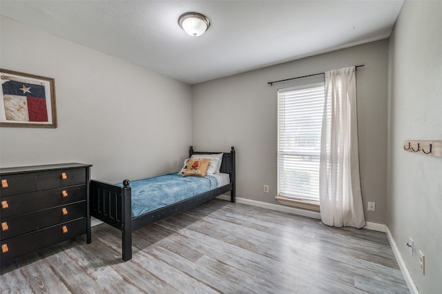 bedroom with baseboards, multiple windows, and wood finished floors