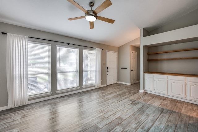 unfurnished living room with a ceiling fan, baseboards, lofted ceiling, and light wood-type flooring