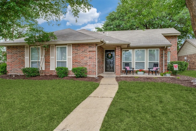 ranch-style house featuring brick siding, a shingled roof, and a front lawn