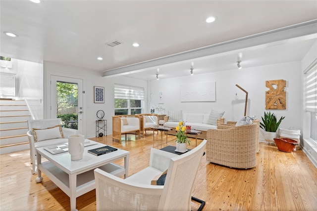 living room with stairs, visible vents, and light wood-style flooring