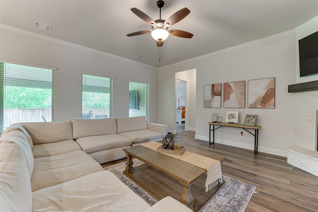 living area featuring visible vents, a ceiling fan, wood finished floors, and ornamental molding