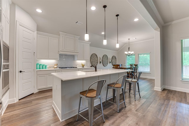 kitchen with crown molding, white cabinets, a sink, appliances with stainless steel finishes, and a notable chandelier