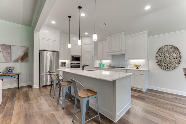 kitchen featuring visible vents, a kitchen bar, white cabinetry, a sink, and appliances with stainless steel finishes