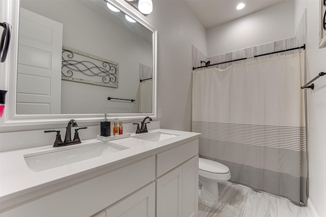 full bathroom with double vanity, a sink, marble finish floor, and toilet