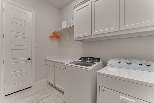 clothes washing area with baseboards, washing machine and dryer, and cabinet space