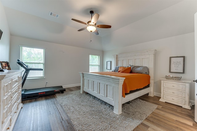 bedroom featuring visible vents, wood finished floors, vaulted ceiling, and multiple windows