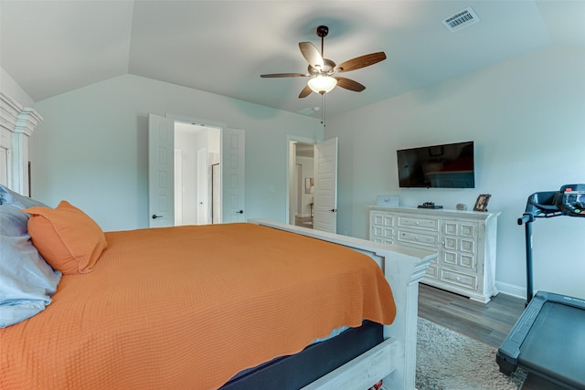 bedroom with a ceiling fan, visible vents, vaulted ceiling, wood finished floors, and baseboards