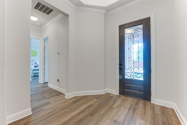 foyer entrance featuring baseboards, visible vents, ornamental molding, and wood finished floors