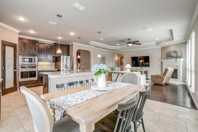 dining space featuring visible vents, arched walkways, a ceiling fan, and a tray ceiling