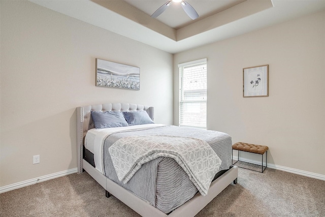 bedroom featuring carpet floors, baseboards, ceiling fan, and a raised ceiling