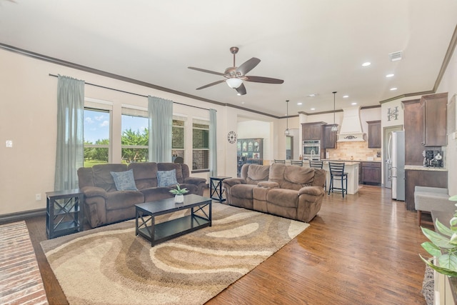 living area featuring ceiling fan, ornamental molding, recessed lighting, and wood finished floors