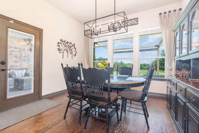 dining space with a chandelier, baseboards, and dark wood-type flooring