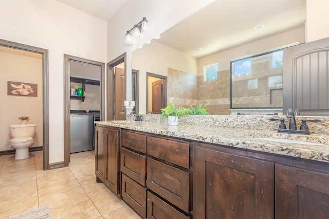 bathroom featuring toilet, washer and dryer, a sink, tile patterned floors, and double vanity