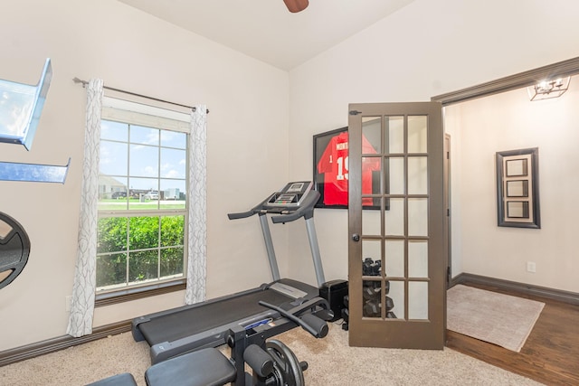 workout room with plenty of natural light, vaulted ceiling, wood finished floors, and baseboards