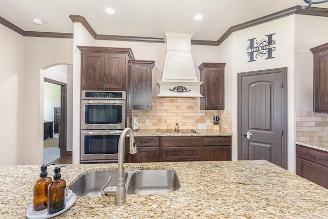 kitchen featuring a sink, stainless steel double oven, dark brown cabinetry, decorative backsplash, and black electric stovetop