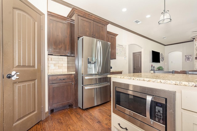 kitchen featuring dark wood-style flooring, ornamental molding, visible vents, arched walkways, and stainless steel appliances