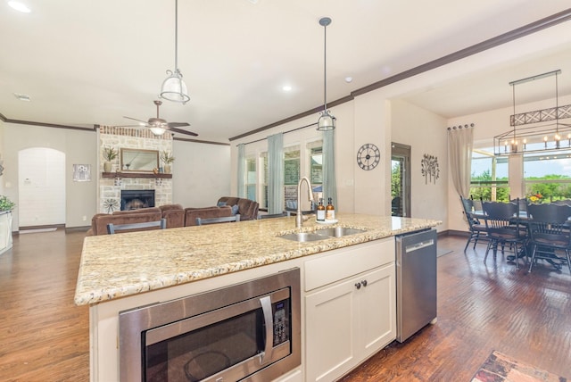 kitchen featuring a sink, ornamental molding, dark wood-type flooring, a fireplace, and appliances with stainless steel finishes