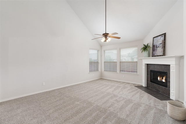 unfurnished living room with ceiling fan, a tiled fireplace, carpet floors, baseboards, and high vaulted ceiling