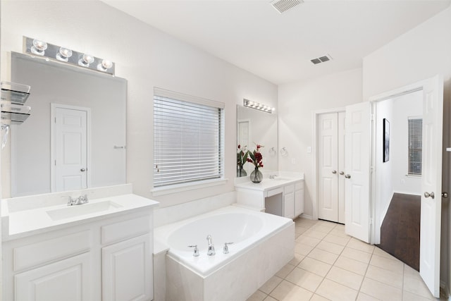 full bathroom with a sink, two vanities, a bath, and visible vents