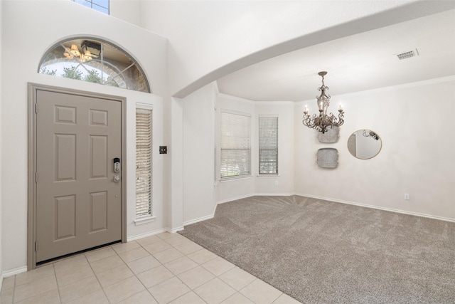 foyer entrance with an inviting chandelier, visible vents, light carpet, baseboards, and arched walkways