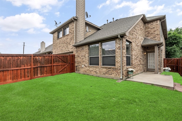 rear view of house with brick siding, a fenced backyard, a chimney, a lawn, and a patio