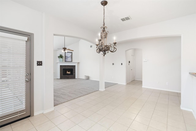 interior space with arched walkways, a warm lit fireplace, visible vents, and ceiling fan with notable chandelier