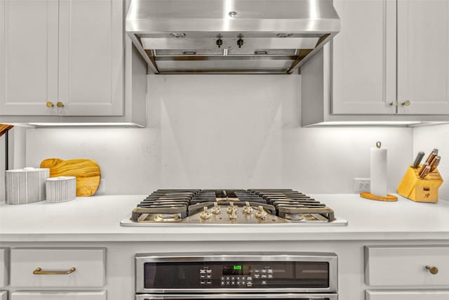 kitchen featuring light countertops, range hood, stainless steel gas stovetop, and oven