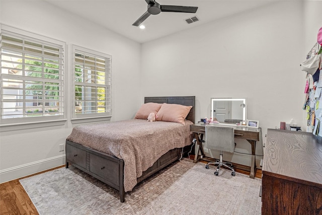 bedroom featuring visible vents, baseboards, wood finished floors, and multiple windows