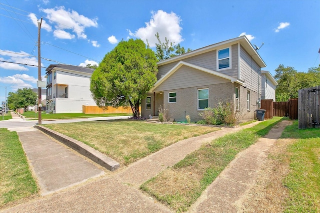 view of property exterior featuring fence, a lawn, and brick siding