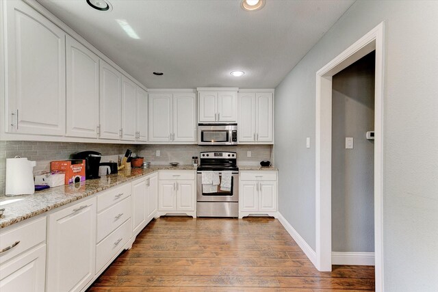 kitchen featuring light stone counters, stainless steel appliances, white cabinetry, wood finished floors, and tasteful backsplash