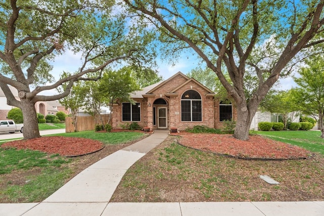 ranch-style house featuring brick siding, fence, and a front yard