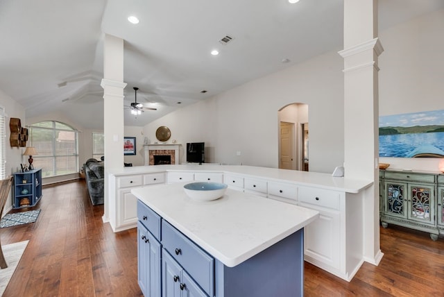 kitchen with lofted ceiling, a fireplace, open floor plan, ceiling fan, and ornate columns