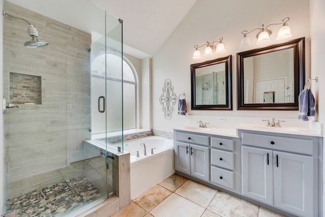 full bathroom with double vanity, a garden tub, vaulted ceiling, a stall shower, and a sink