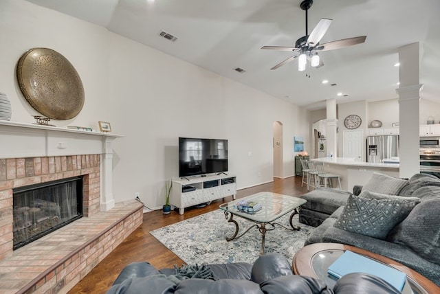 living area with ceiling fan, visible vents, arched walkways, a fireplace, and dark wood-type flooring
