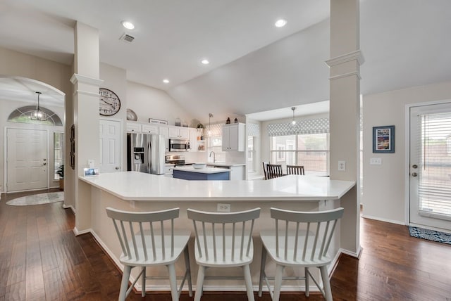 kitchen featuring visible vents, dark wood-style flooring, lofted ceiling, ornate columns, and appliances with stainless steel finishes