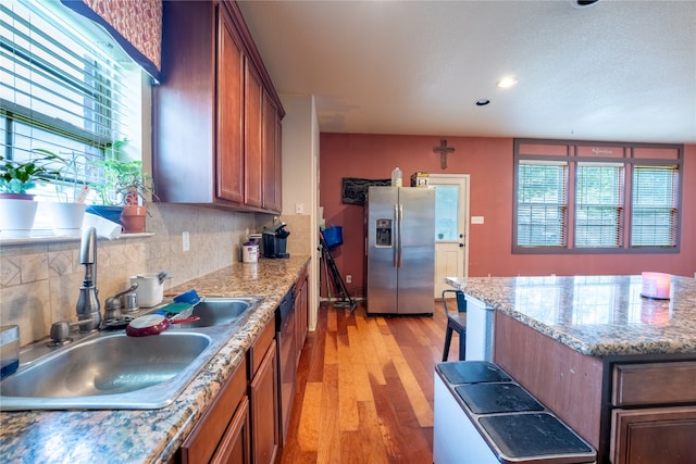 kitchen featuring plenty of natural light, a sink, stainless steel fridge with ice dispenser, and light wood-style floors