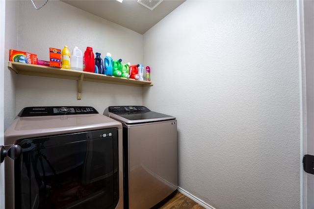 laundry area with laundry area, visible vents, washing machine and dryer, wood finished floors, and baseboards