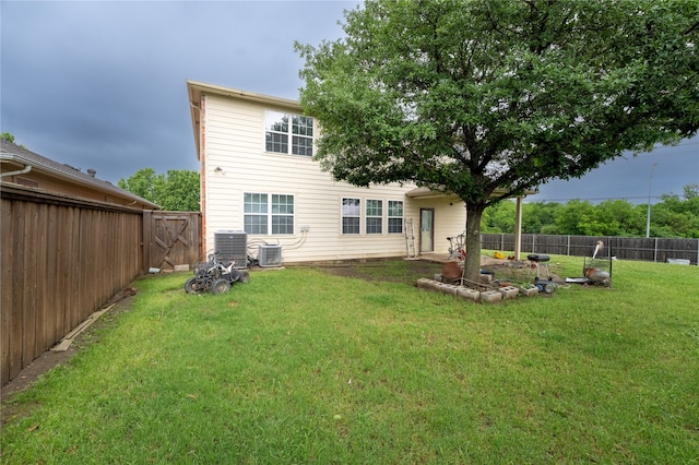 rear view of house featuring a lawn, cooling unit, and a fenced backyard