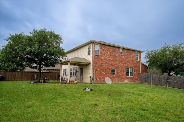 rear view of property with a fenced backyard, a ceiling fan, and a lawn