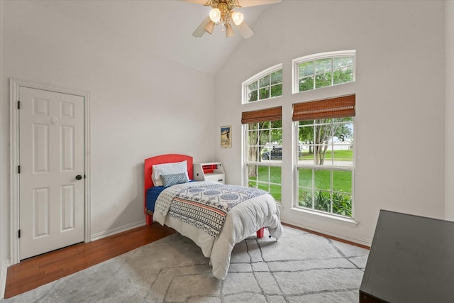 bedroom featuring high vaulted ceiling, baseboards, a ceiling fan, and wood finished floors