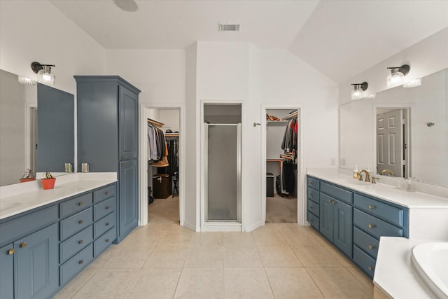 bathroom featuring visible vents, tile patterned floors, a shower stall, a sink, and vaulted ceiling